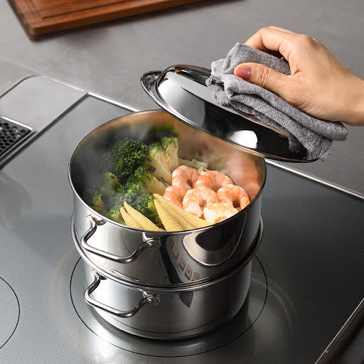 Compact stainless steel steamer with vegetables and shrimp inside, perfectly steaming ingredients for a healthy and delicious meal.