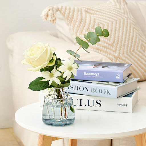 A charming vase filled with flowers sits on a table, accompanied by a stack of books, adding warmth to the space.