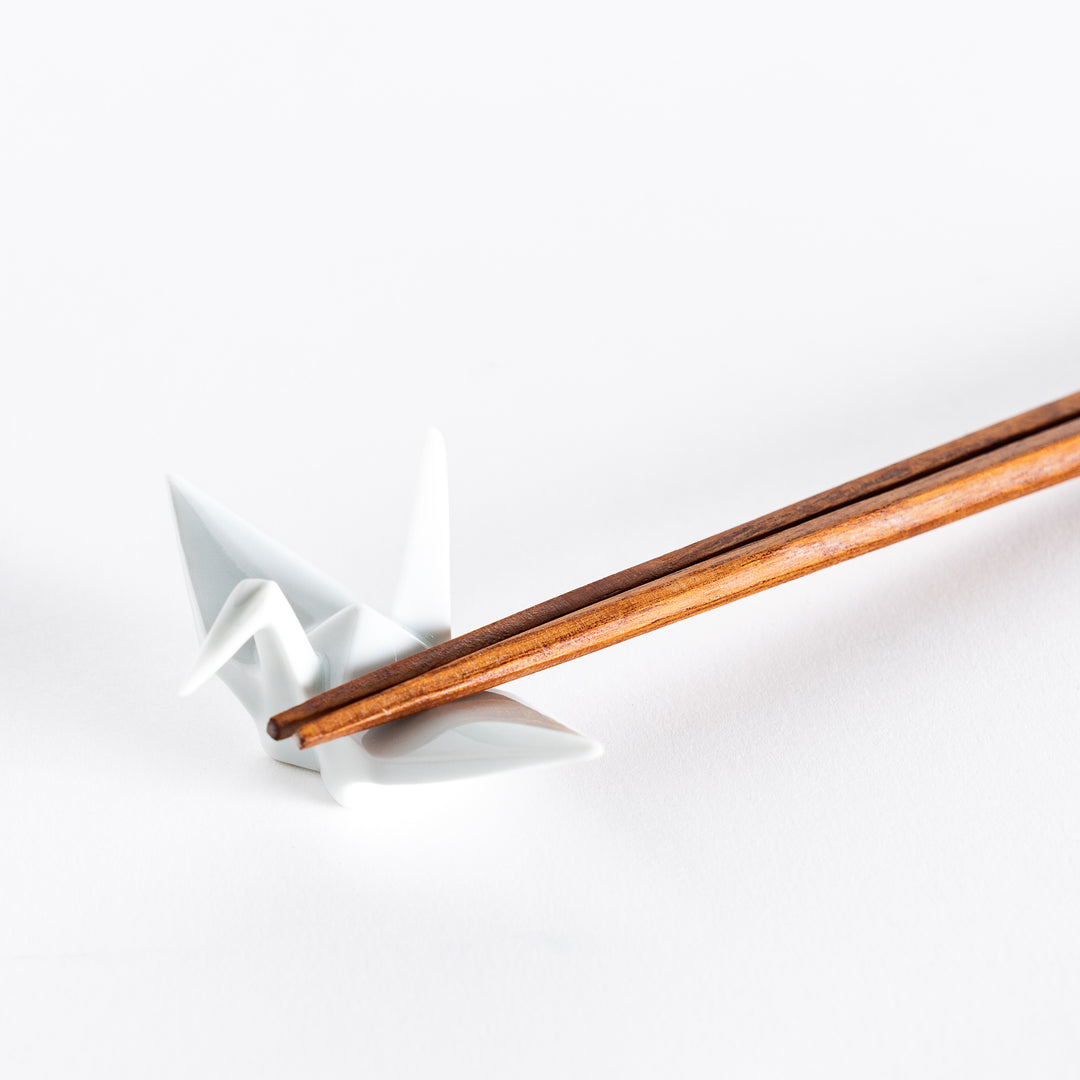 Close-up of chopsticks resting on the white ceramic crane-shaped chopstick rest.