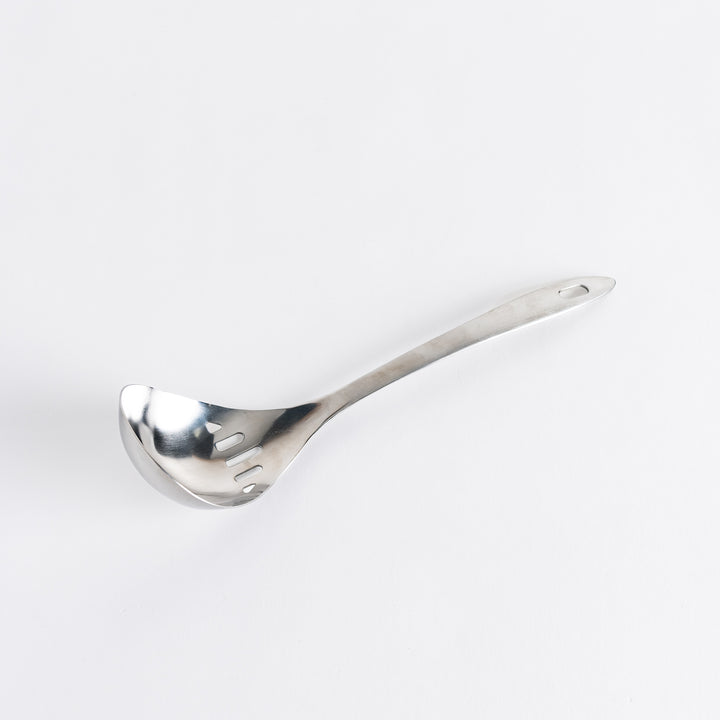 A stainless steel ladle with small drainage holes and a wide, deep scoop, designed for straining while serving.