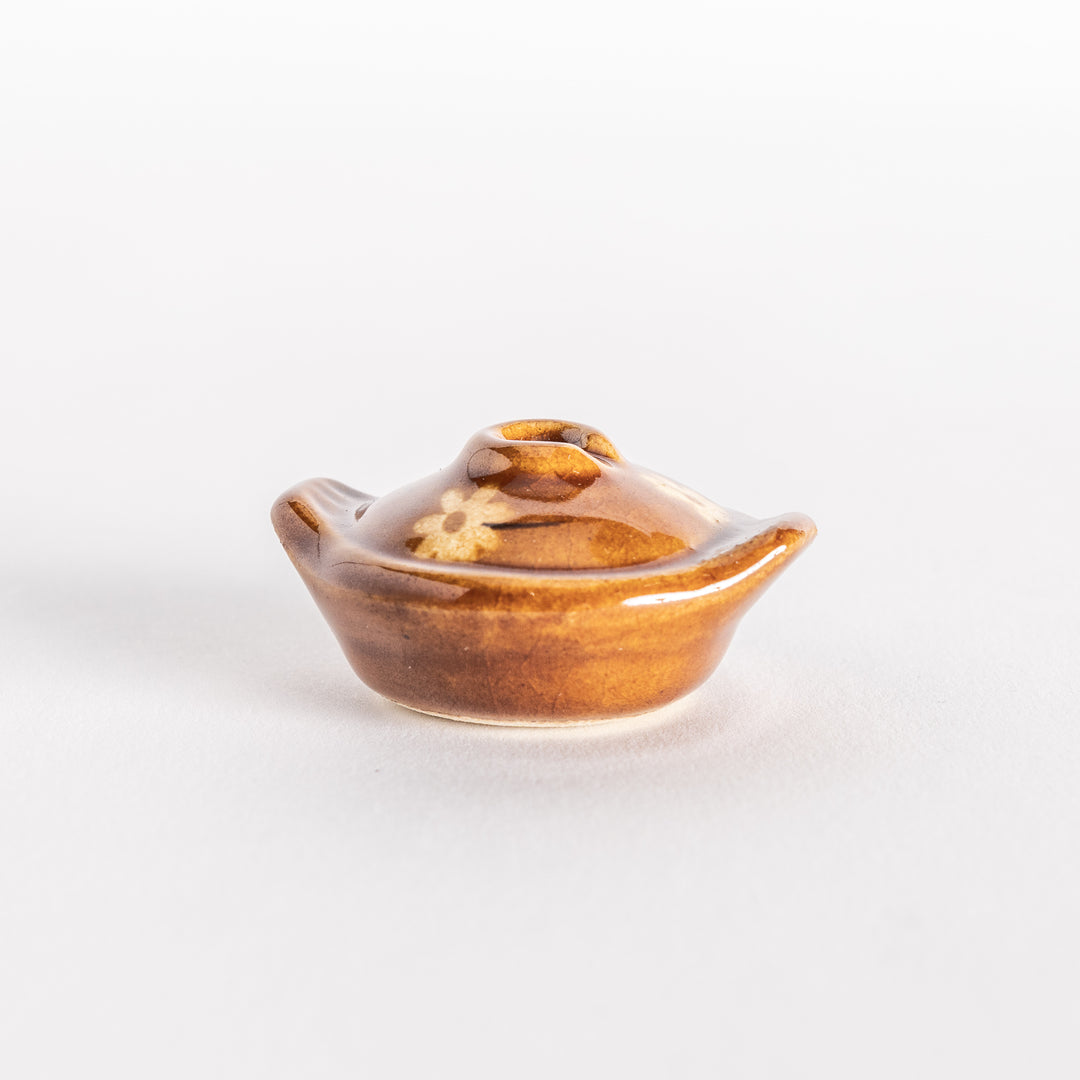 Side view of the amber earthen pot chopsticks rest, highlighting its rounded shape and elegant curve.