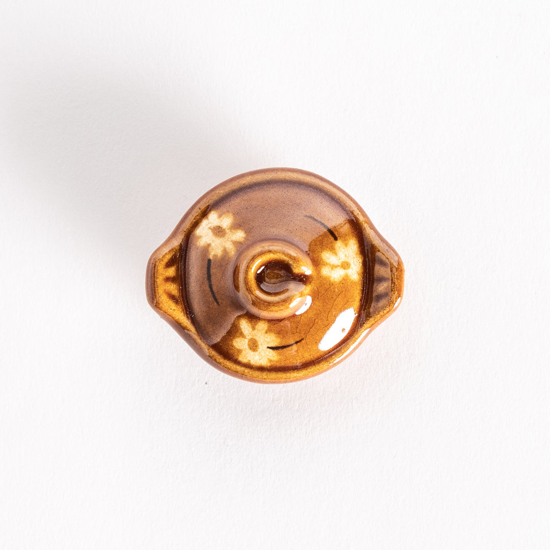 Top-down view of the amber earthen pot chopsticks rest, clearly showing its floral patterns and lid design.