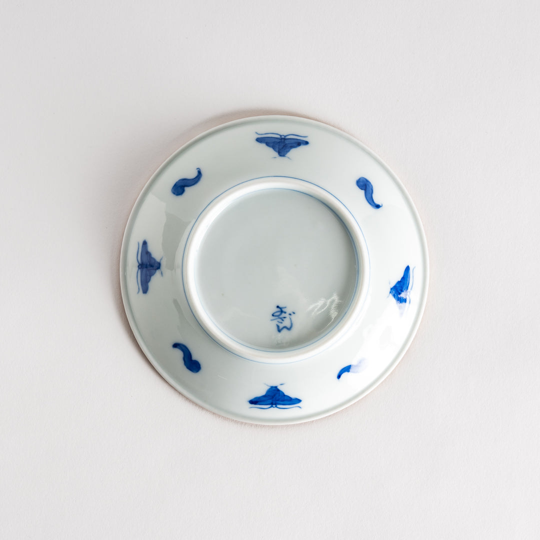 A ceramic plate with an intricate blue floral design centered around a bold circular pattern, framed by a copper-colored textured rim.