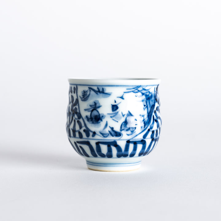 Side view of a sake cup featuring an intricate blue arabesque landscape design with fish, waves, and floral elements.