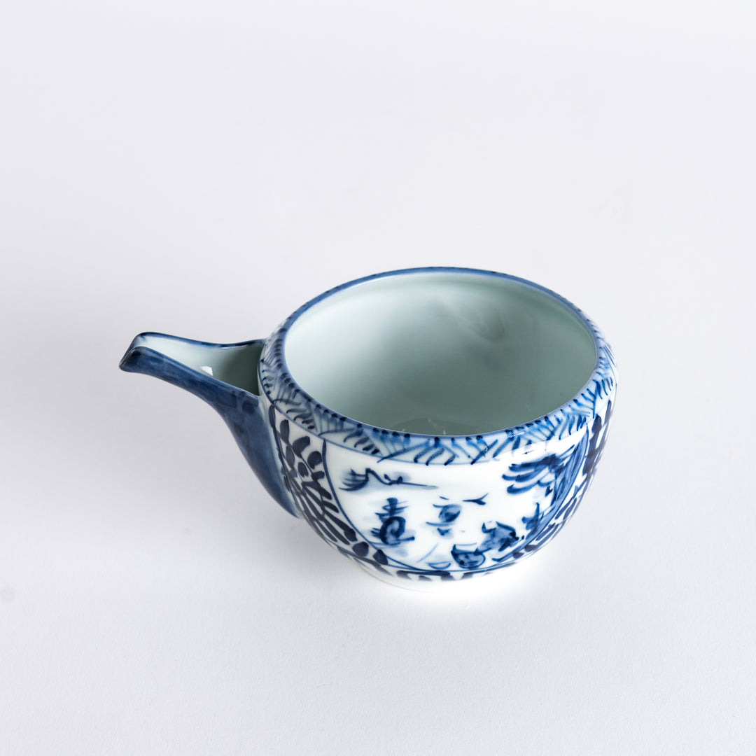 Angled view of the sake pourer, with a visible spout and intricate blue arabesque landscape pattern.