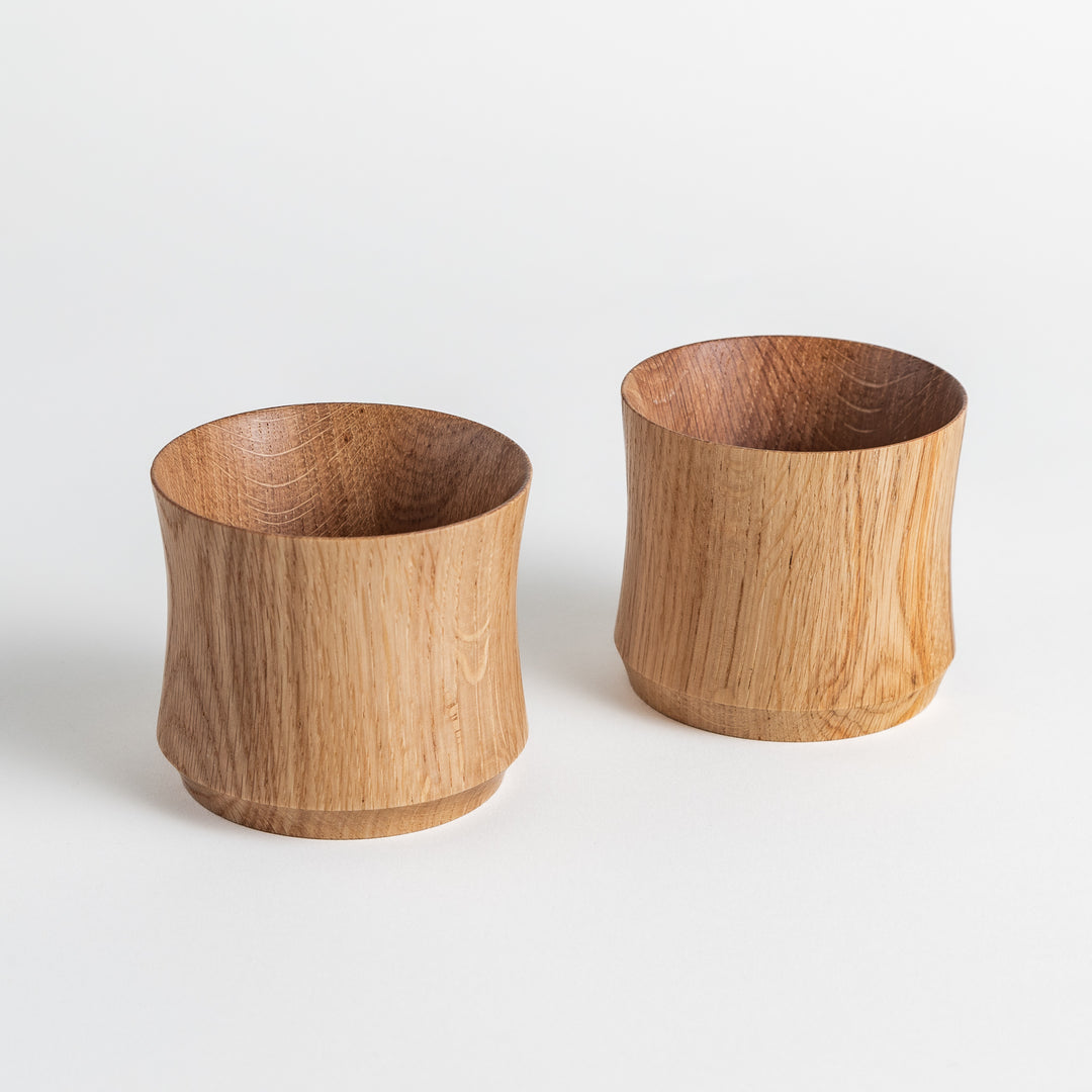 Two Artisan Mizunara Oak whisky cups with natural wood grain, showcasing their smooth shape and unique, organic design.