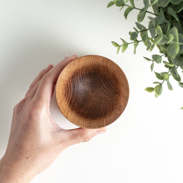 Hand holding one Artisan Mizunara Oak whisky cup, emphasizing the elegant curvature and rich wood texture.