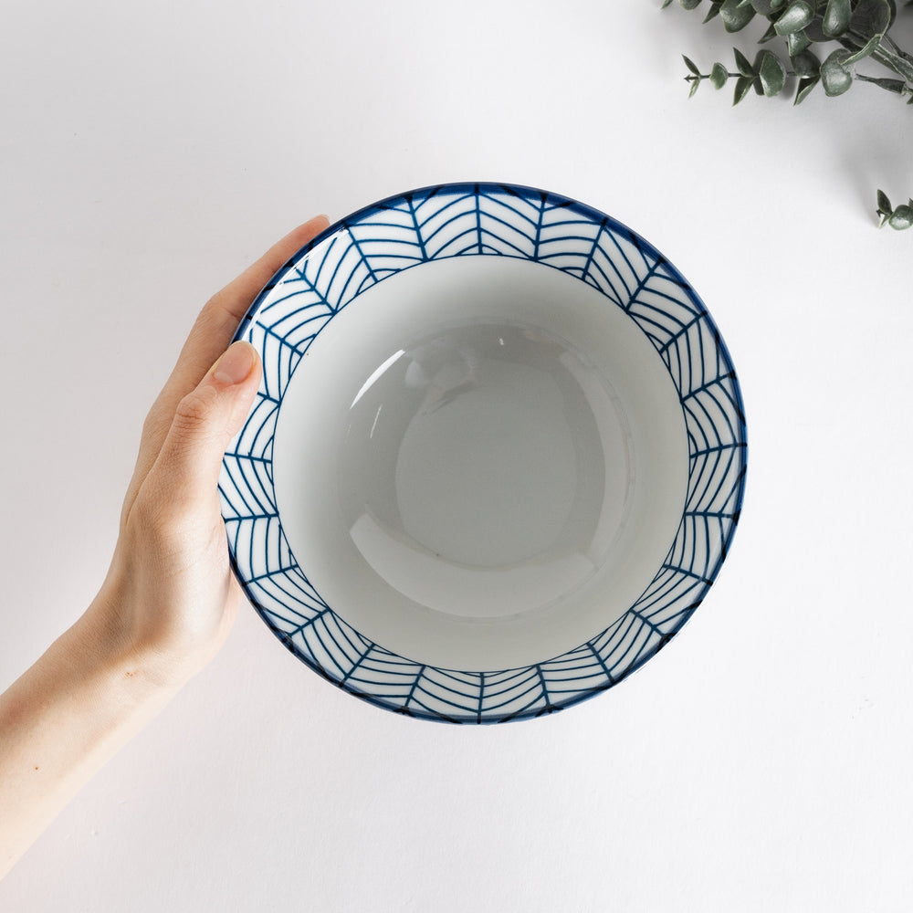 Ceramic ramen bowl with blue striped pattern on white background.