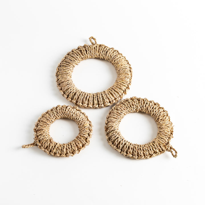 Set of three natural rush trivets in varying sizes, each with a loop for hanging, perfect for protecting surfaces.