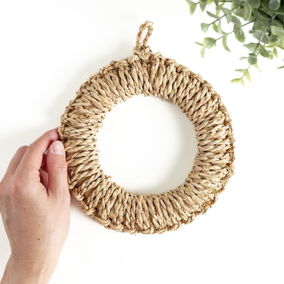 A hand holding a medium-sized straw trivet. Its woven texture and durable material are clearly visible, perfect for everyday use.