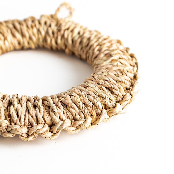 A close-up of a straw trivet with clear focus on its round shape and natural woven fibers. A versatile piece for any dining setup.