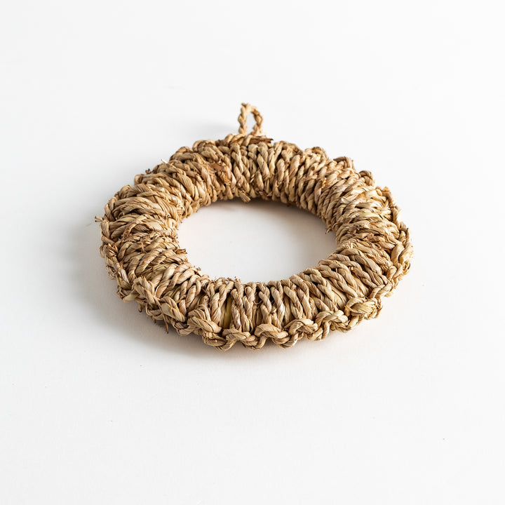 Artisan rush trivet in natural tones, round with a textured surface, ideal for serving dishes.