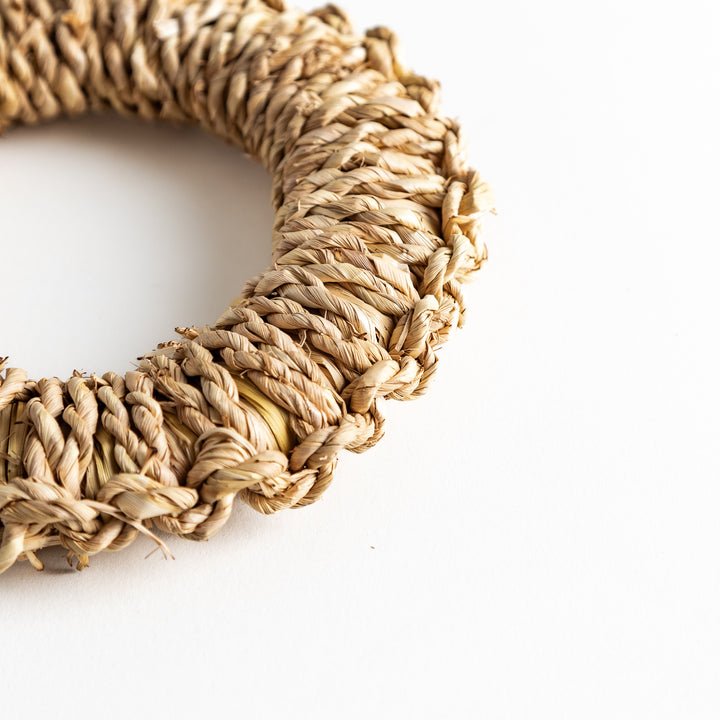 Close-up of an artisan rush trivet showing the intricate braided texture and a circular shape.