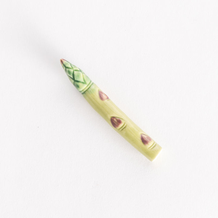 A ceramic asparagus chopsticks rest with realistic green and purple accents.