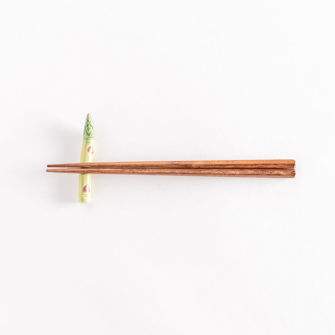 Ceramic asparagus chopsticks rest with chopsticks positioned across its surface.