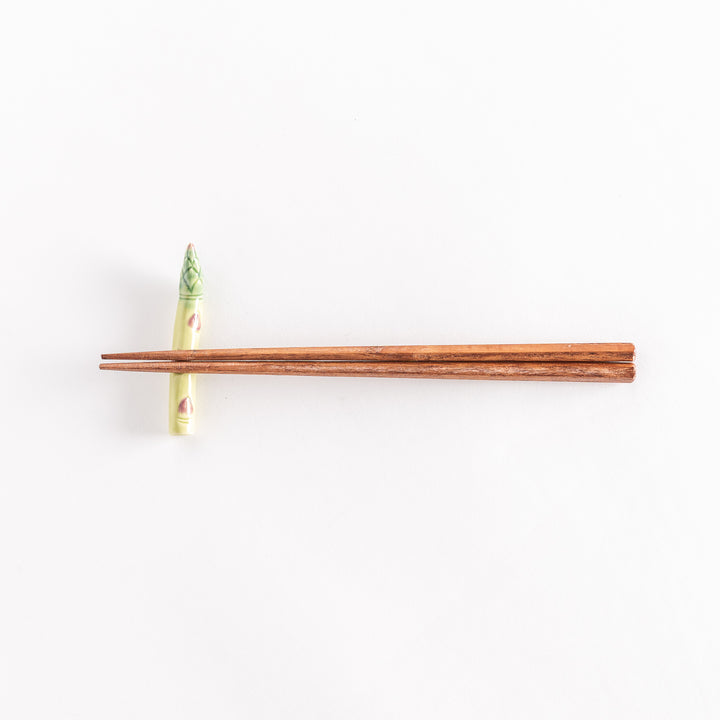 Ceramic asparagus chopsticks rest with chopsticks positioned across its surface.