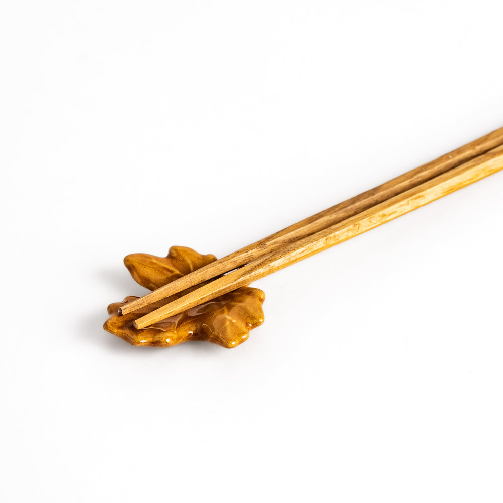 Autumn Maple Leaf Chopstick Rest holding wooden chopsticks, showcasing its intricate leaf design and functional, elegant style.