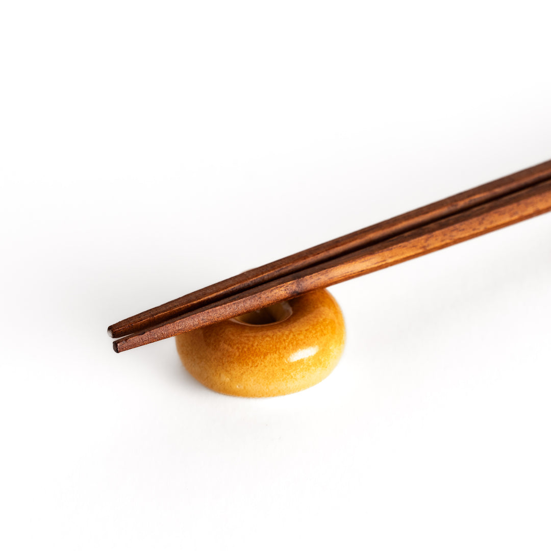 Close-up view of chopsticks resting on the bagel-shaped chopsticks rest, emphasizing its lifelike texture and details.