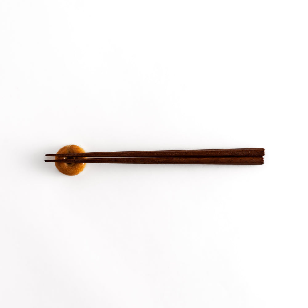 Bagel-shaped chopsticks rest with chopsticks placed on it, viewed from a distance to highlight its functionality and charm.