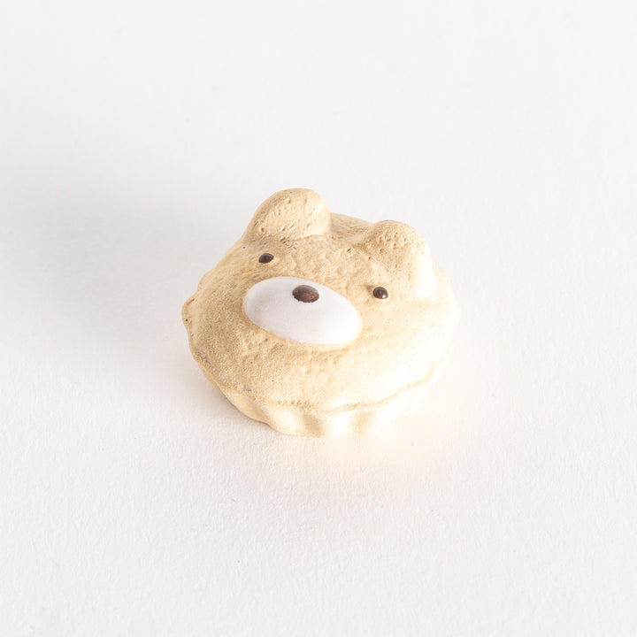 A beige ceramic chopstick rest shaped like a bear face in a cupcake design, featuring detailed facial features.