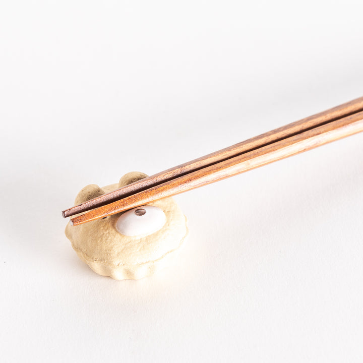 A close-up view of the bear-shaped cupcake ceramic chopstick rest with chopsticks resting on its surface.