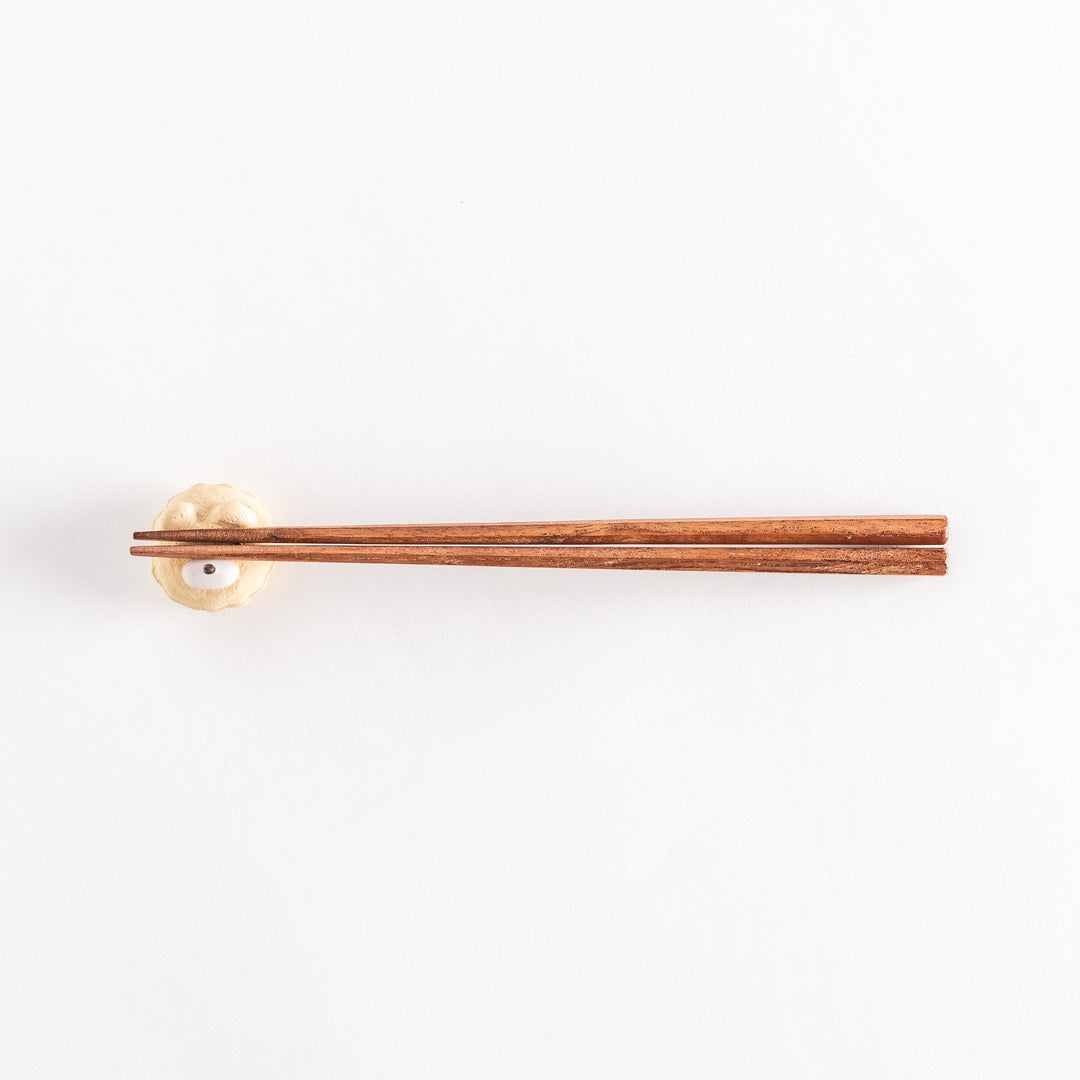 A wider view of the bear cupcake ceramic chopstick rest with chopsticks placed on it, highlighting its playful design.