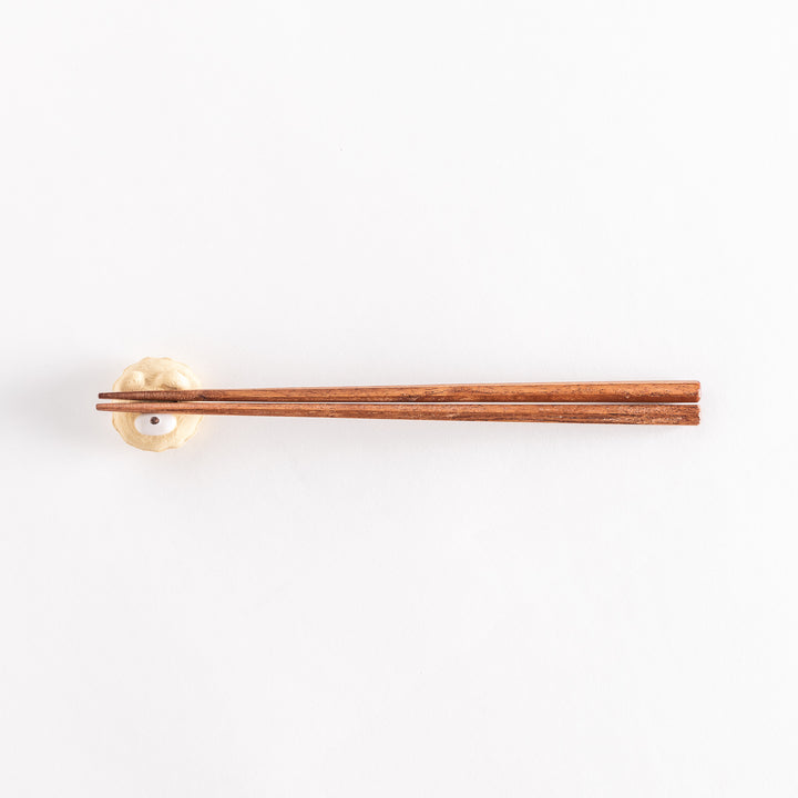 A wider view of the bear cupcake ceramic chopstick rest with chopsticks placed on it, highlighting its playful design.