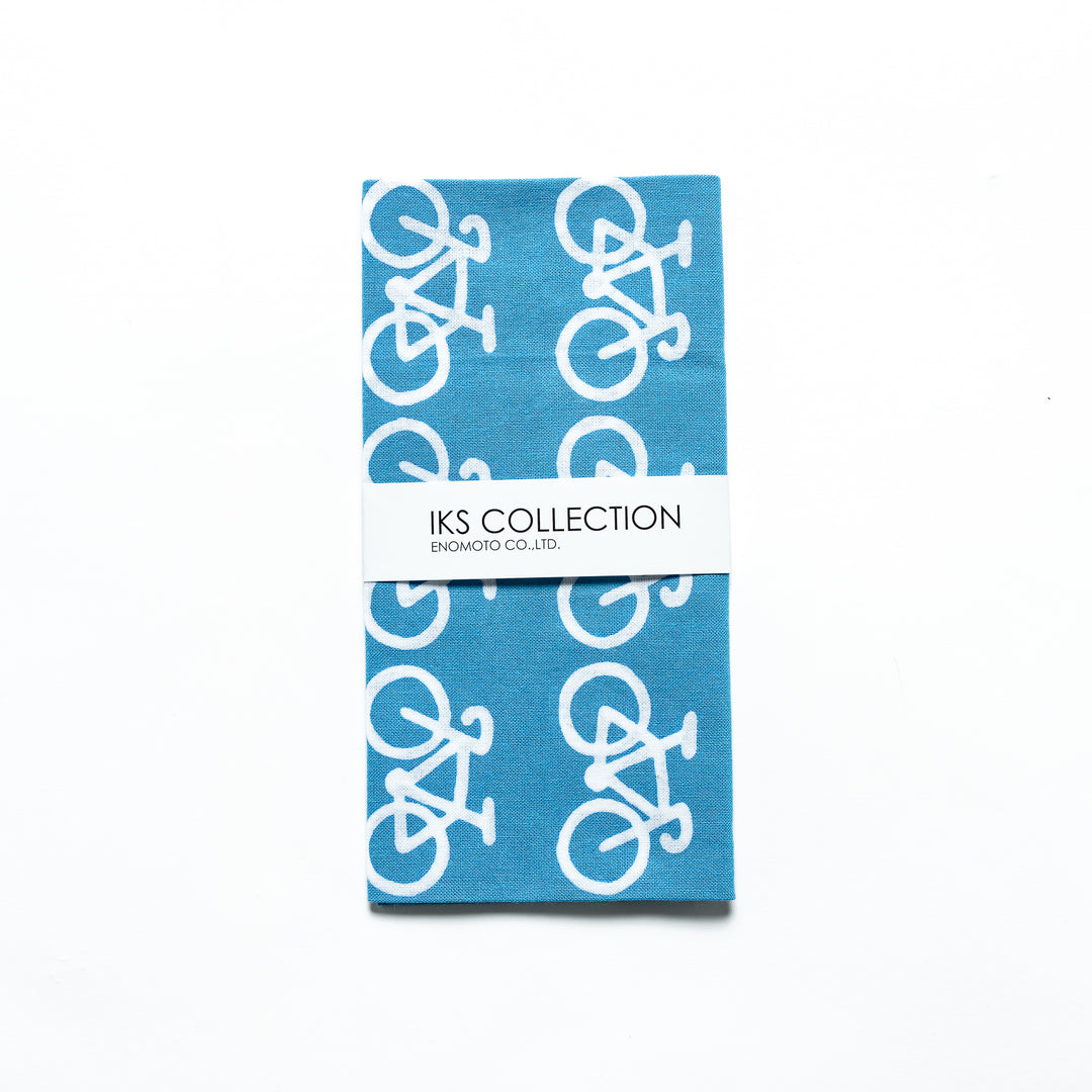 The blue tenugui is neatly folded, showcasing a product sleeve with the bicycle motif.