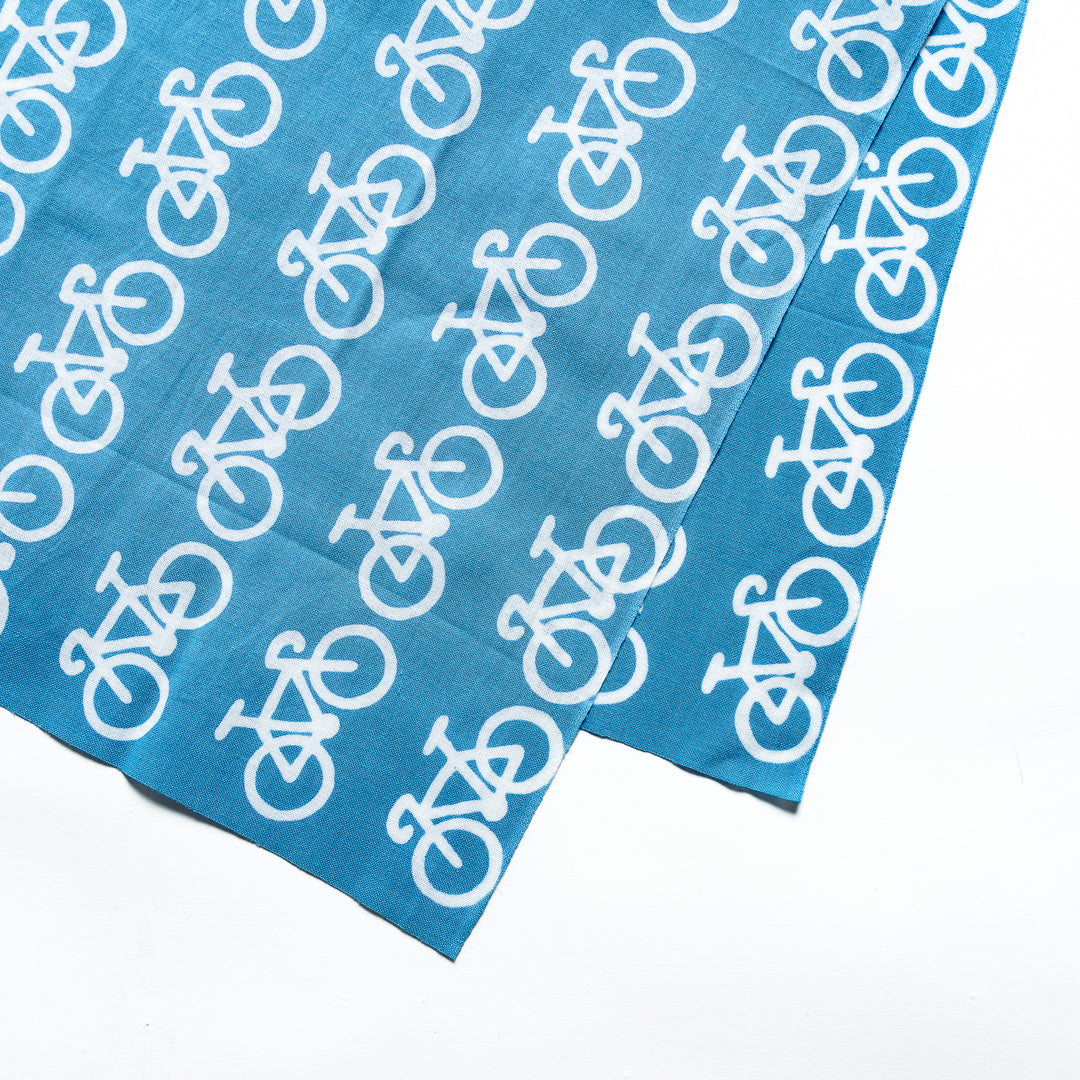 Close-up view of the white bicycle design on the vibrant blue fabric.