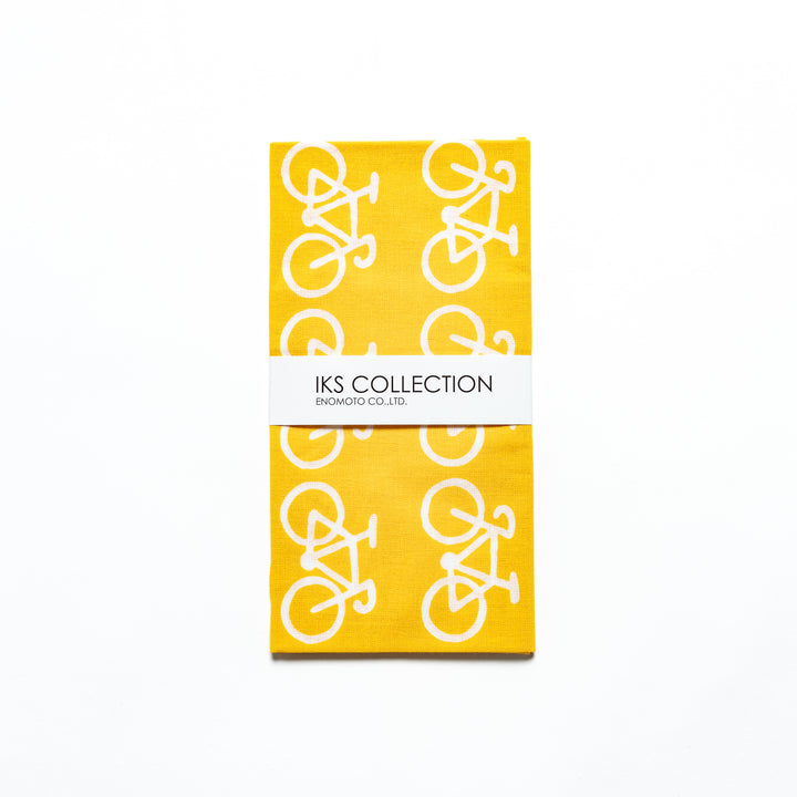 The yellow tenugui is neatly folded, showcasing a product sleeve with the bicycle motif.