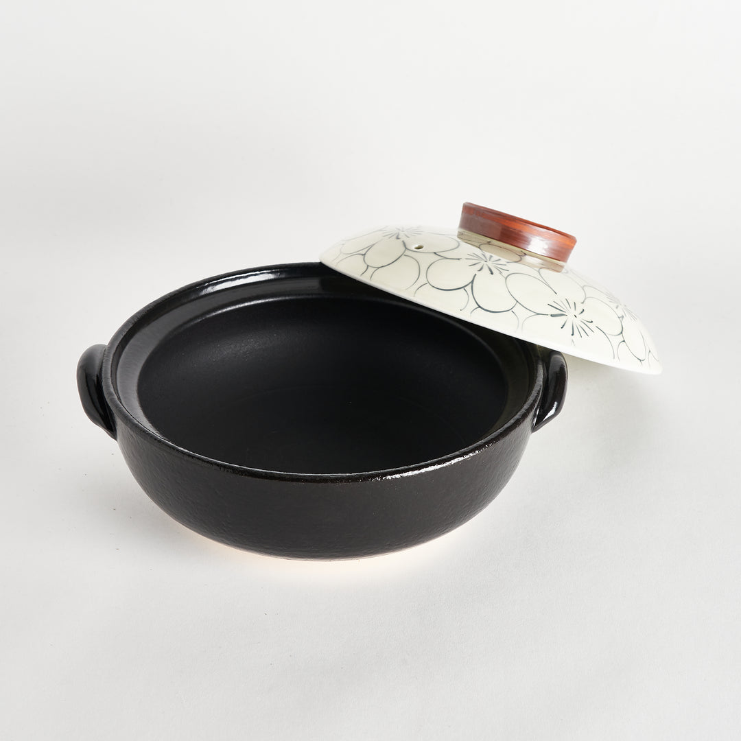 Donabe with lid slightly lifted, revealing a spacious black interior for cooking and serving delicious meals.