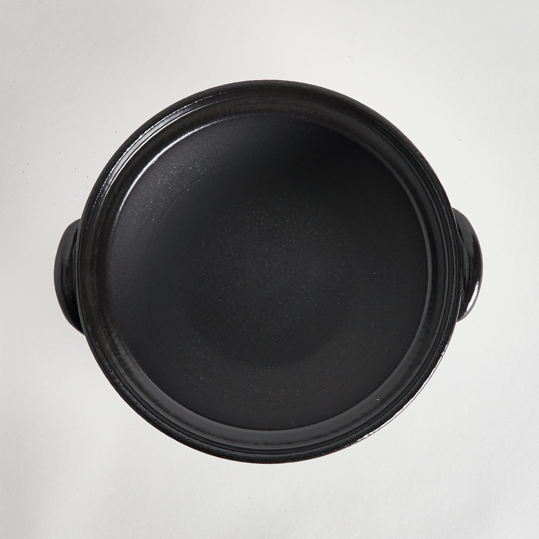 Overhead view of the black interior of the donabe, highlighting its smooth and spacious cooking surface.