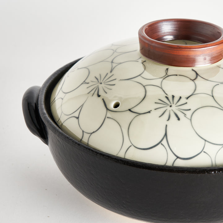 Close-up of donabe lid with delicate floral pattern and brown rim, emphasizing its traditional craftsmanship.