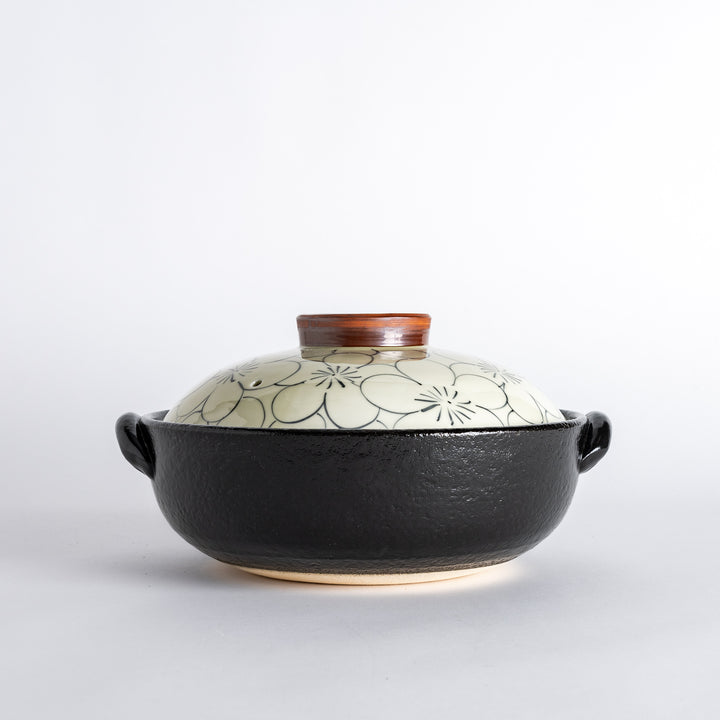 A donabe with a vibrant black floral pattern lid and black pot.