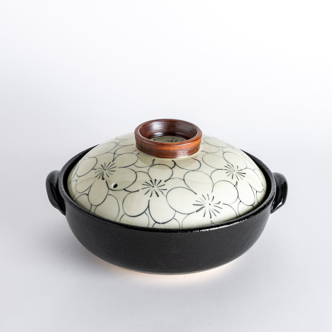 A donabe with a vibrant black floral pattern lid and black pot.