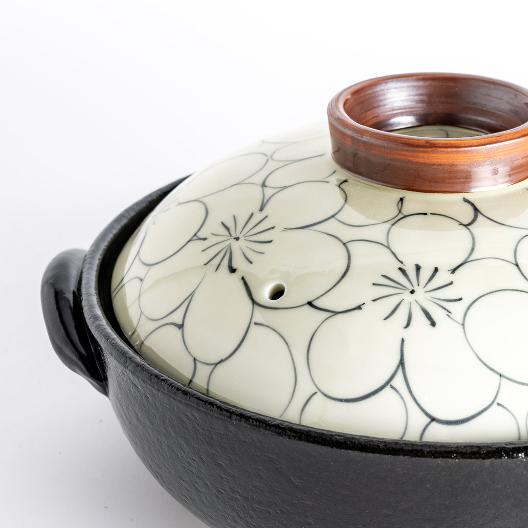 A donabe with a vibrant black floral pattern lid and black pot.