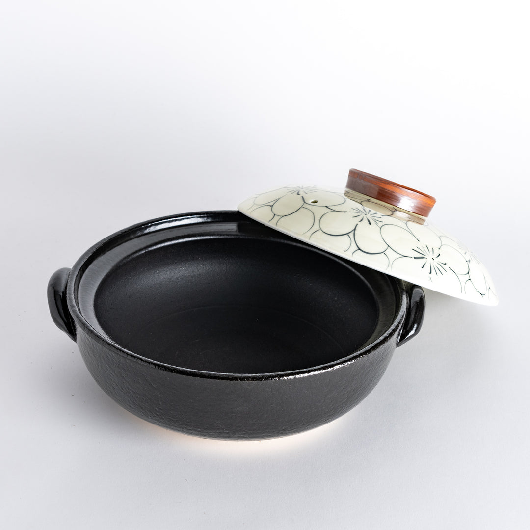 A donabe with a vibrant black floral pattern lid and black pot.