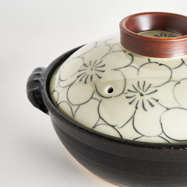 Close-up of donabe lid with cream floral patterns and a small steam hole, highlighting brown ring.