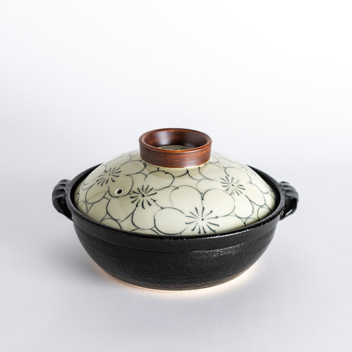 A 8-inch donabe with a vibrant black floral pattern lid and black pot.