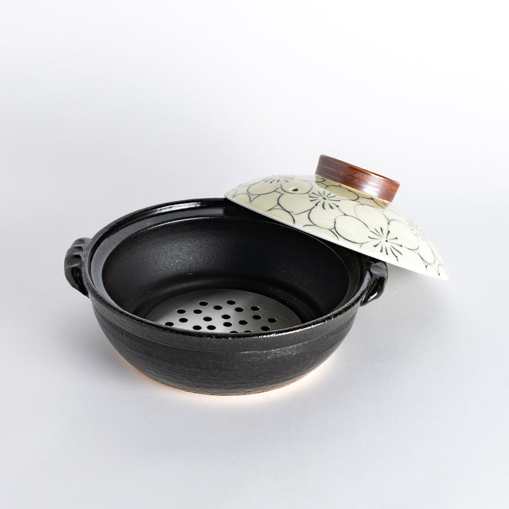 A 8-inch donabe with a vibrant black floral pattern lid and black pot.