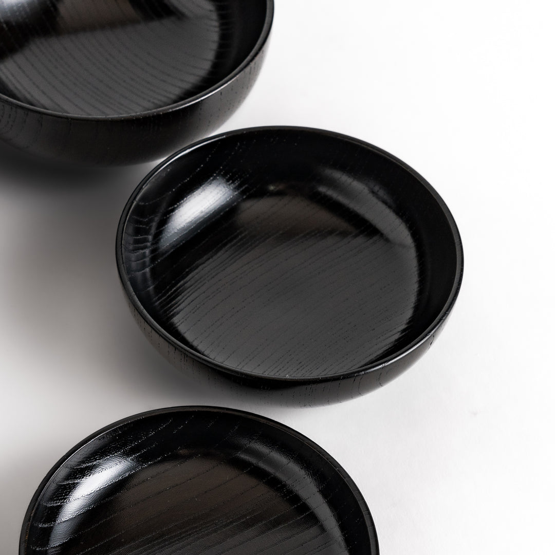 Black lacquered Oryoki bowl set featuring a large serving bowl, three medium bowls, and three small plates with a glossy finish.