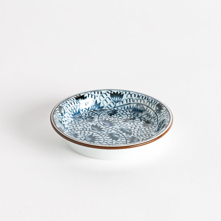 A small saucer adorned with detailed blue leaf patterns on a white background.