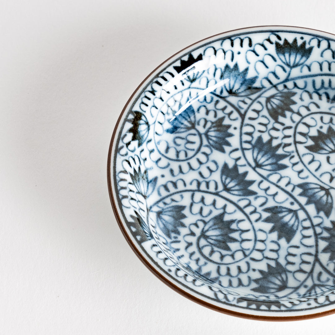 A small saucer adorned with detailed blue leaf patterns on a white background.