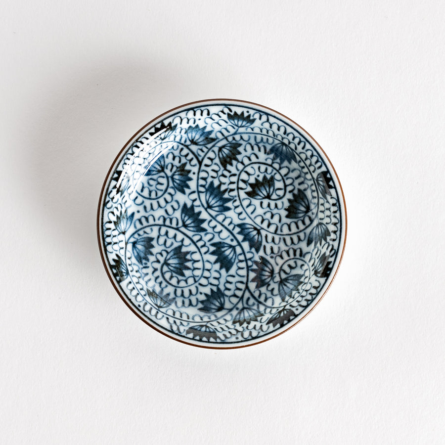 A small saucer adorned with detailed blue leaf patterns on a white background.