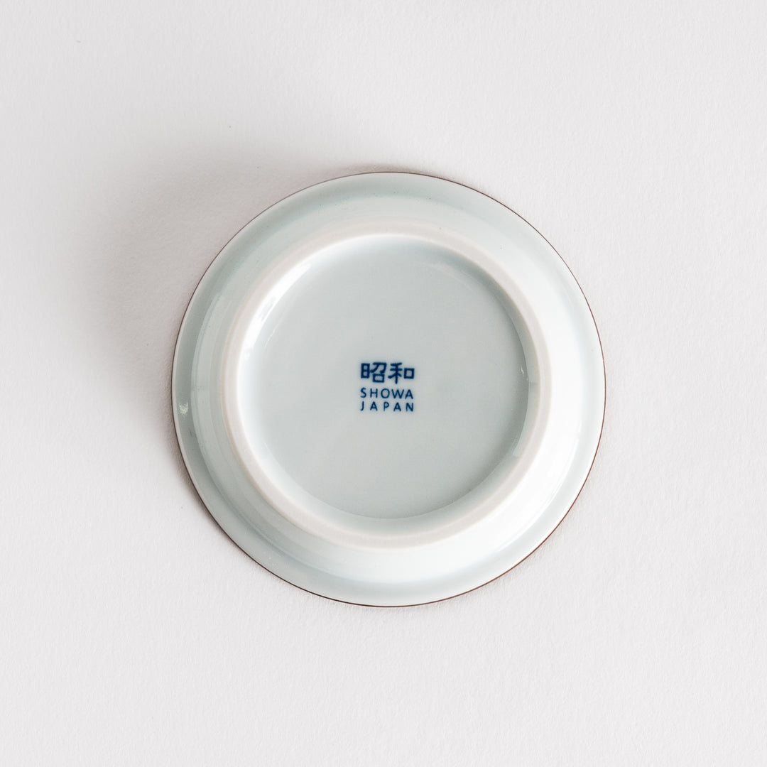 A small saucer adorned with detailed blue leaf patterns on a white background.