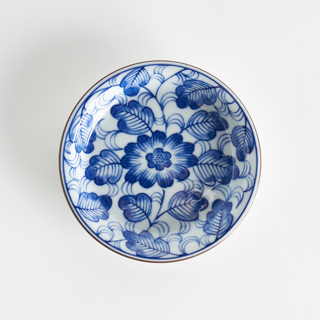 A round saucer featuring a delicate blue floral design on a white background.