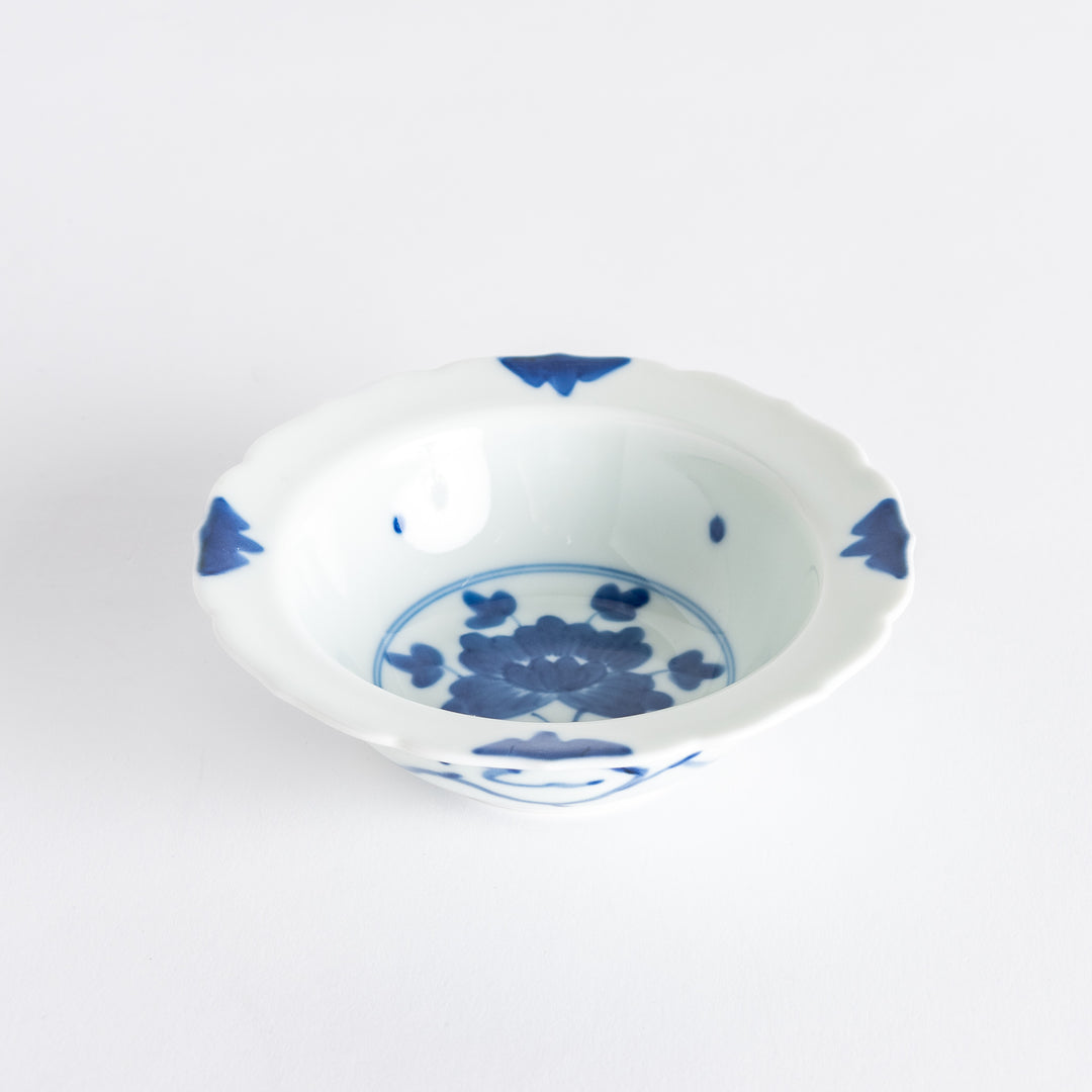 A dessert bowl with blue peony flower motifs at the center and on the rim, framed by soft scalloped edges.