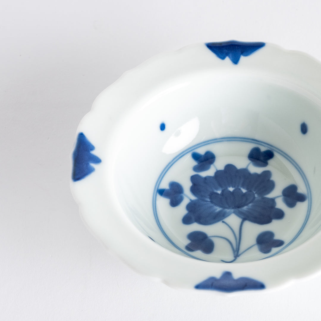 A dessert bowl with blue peony flower motifs at the center and on the rim, framed by soft scalloped edges.