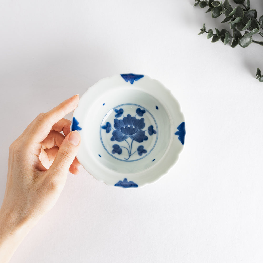 A dessert bowl with blue peony flower motifs at the center and on the rim, framed by soft scalloped edges.