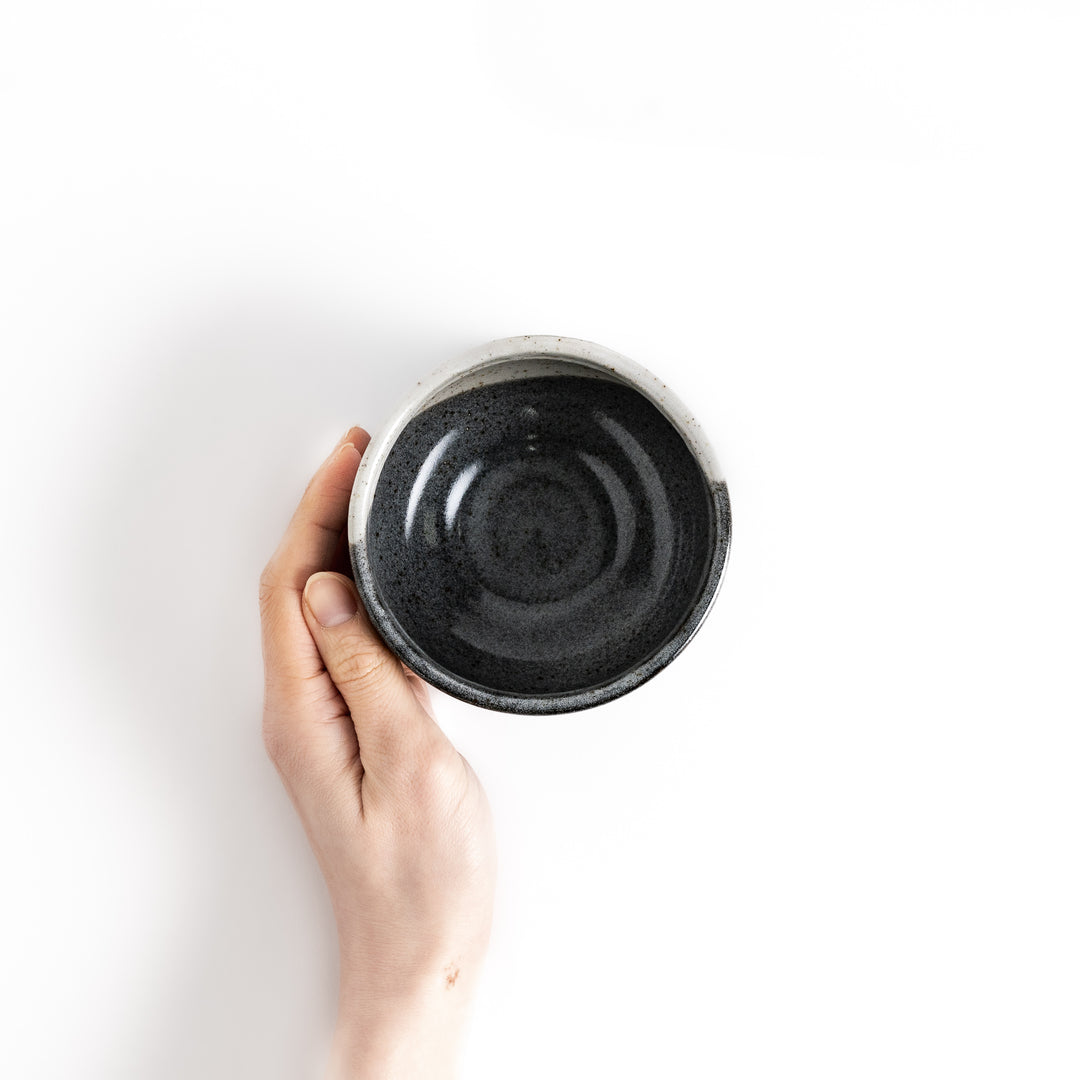 and holding a matcha bowl with a contrasting glaze, ideal for whisking and enjoying a ceremonial cup of matcha.